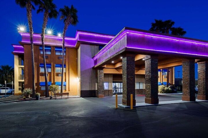 Best Western McCarran Inn hotel exterior at dusk with purple neon lighting, palm trees, and a clear entrance