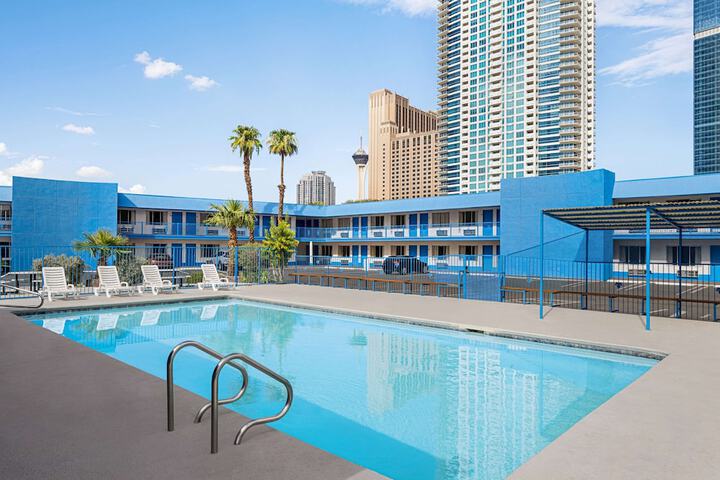 Outdoor pool area of Travelodge by Wyndham hotel with city skyline in the background.