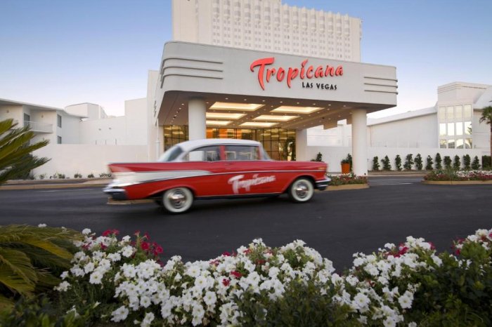 Classic red car passing by the Tropicana Las Vegas hotel entrance.